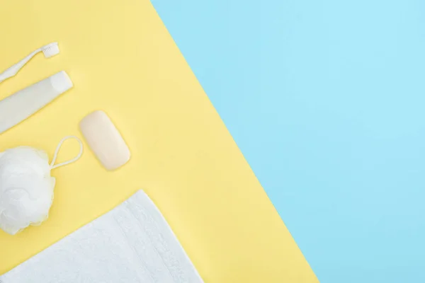 Vista dall'alto di spazzolino da denti, dentifricio, asciugamano, panno e sapone, isolato su blu e giallo — Foto stock