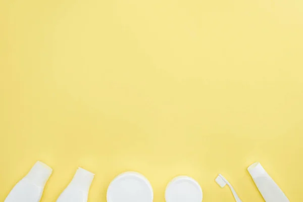 Vue du dessus des récipients et bouteilles en plastique avec crème, dentifrice et brosse à dents, isolés sur jaune — Photo de stock