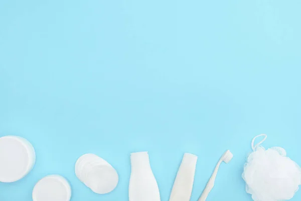 Вид зверху пластикової тарілки і пляшки з кремом, губкою, зубною пастою і зубною щіткою, ізольовані на синьому — стокове фото