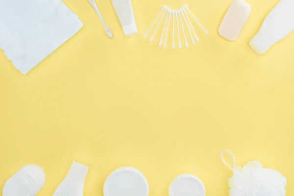 Tendido plano con crema cosmética, loción corporal, esponja, toallas y hisopos de algodón, aislado en amarillo - foto de stock