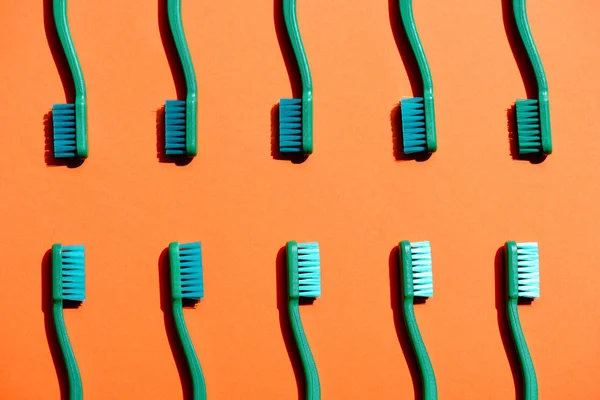 Fondo minimalista con cepillos de dientes verdes, en naranja - foto de stock