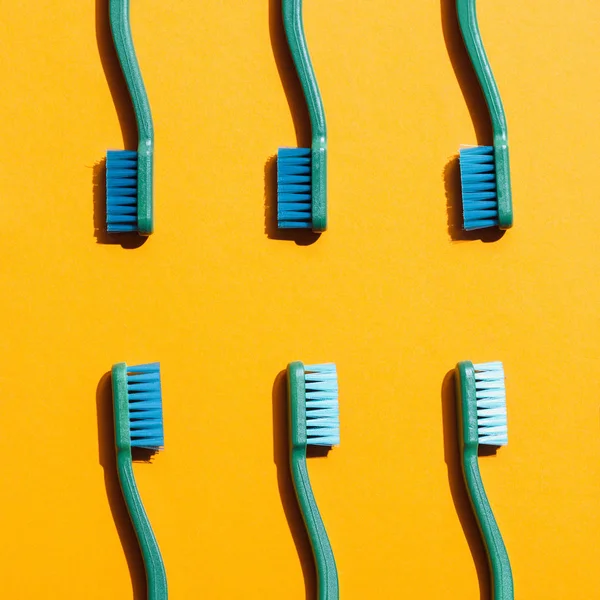 Fondo minimalista con cepillos de dientes verdes, en amarillo - foto de stock
