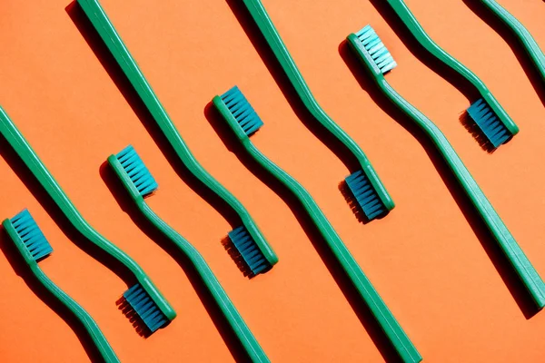 Fundo minimalista com escovas de dentes verdes, em laranja — Fotografia de Stock