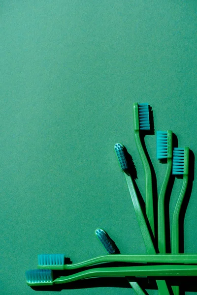 Top view of green toothbrushes, on green with copy space — Stock Photo