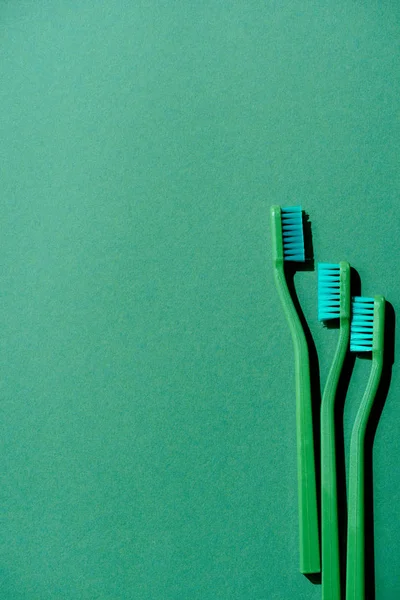 Top view of green toothbrushes, on green with copy space — Stock Photo