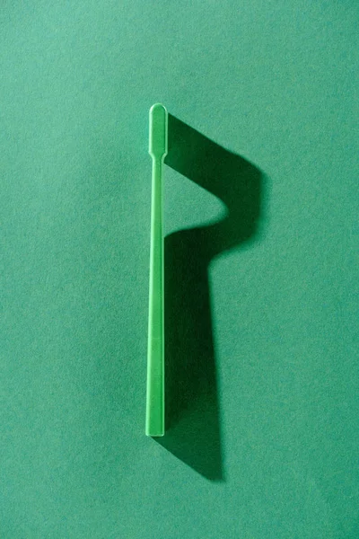 Вид сверху на зеленую зубную щетку с тенью, на зеленый — стоковое фото