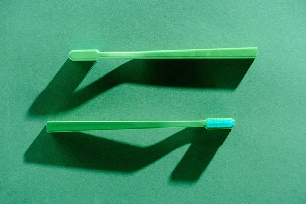 Top view of two green toothbrushes, on green — Stock Photo