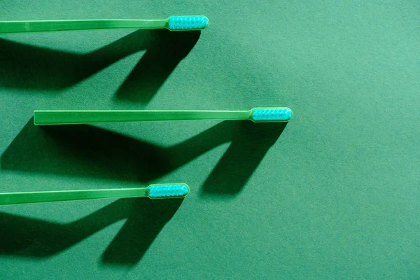 Top view of green toothbrushes, on green — Stock Photo