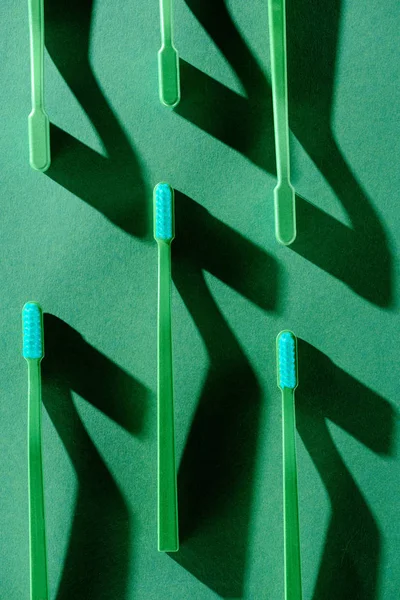 Fond minimaliste avec brosses à dents vertes avec ombres, sur fond vert — Photo de stock