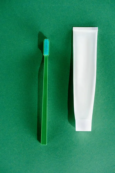 Вид сверху на зубную щетку и тюбик зубной пасты, зеленый — стоковое фото