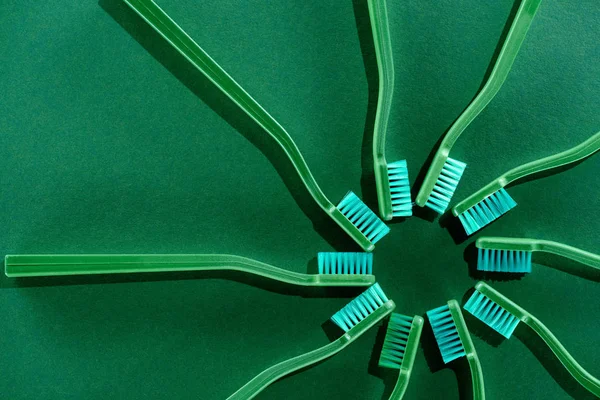Верхний вид композиции круга с зелеными зубными щетками на зеленый — стоковое фото
