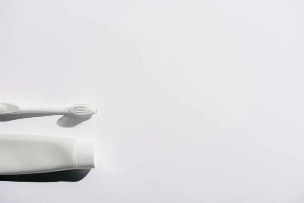 Top view of white toothbrush and toothpaste, on white with copy space — Stock Photo