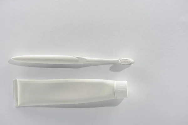 Top view of white toothbrush and tube of toothpaste, on white — Stock Photo