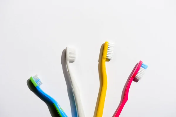 Cuatro cepillos de dientes de colores para la higiene matutina, en blanco - foto de stock