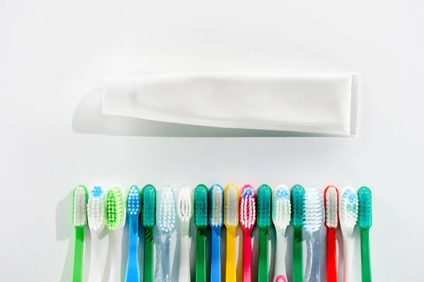 Top view of colorful toothbrushes and tube of toothpaste, on white — Stock Photo