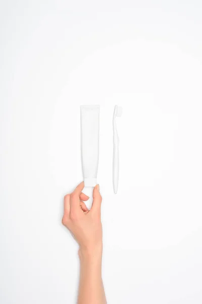Corte da mão feminina com escova de dentes e tubo de pasta de dentes, isolado em branco — Fotografia de Stock