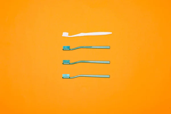 Top view of green and white toothbrushes in row, isolated on orange — Stock Photo