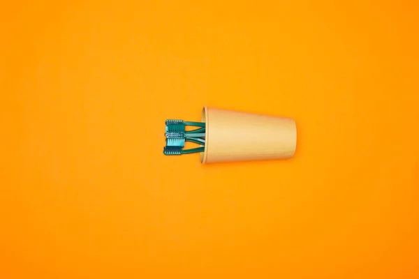 Vista superior de cepillos de dientes en taza de papel, aislado en naranja - foto de stock