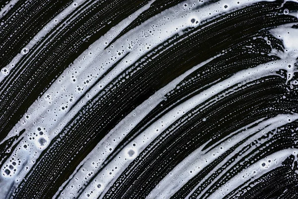 Texture of white soap foam on black surface — Stock Photo