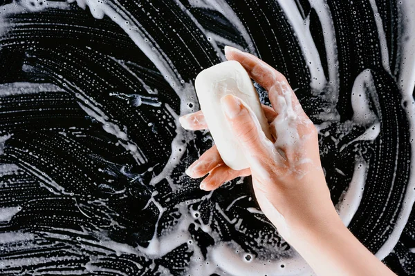 Vista recortada de la mujer que sostiene el jabón con espuma blanca - foto de stock