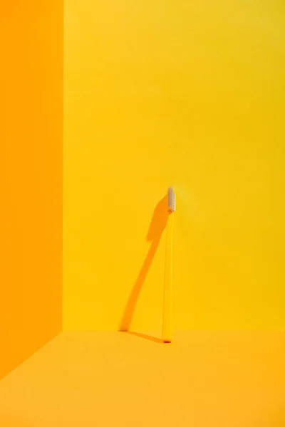 Yellow toothbrush standing at orange wall — Stock Photo