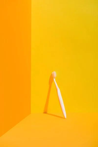 Cepillo de dientes blanco de pie en la pared naranja - foto de stock