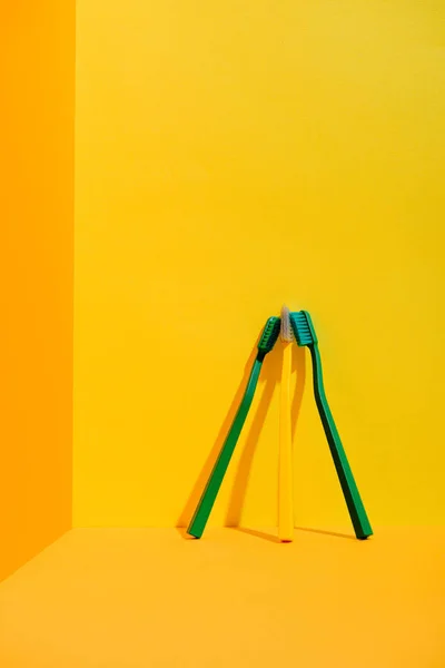 Cepillos de dientes verdes y amarillos en la pared naranja - foto de stock