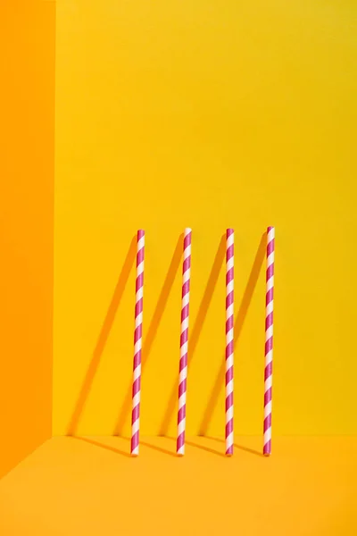 White and red striped straws standing at orange wall — Stock Photo