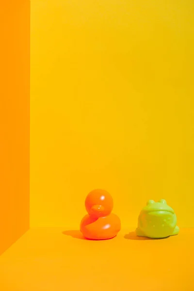 Duck and frog bath toys on yellow with copy space — Stock Photo