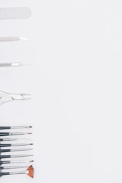 Top view of brushes, scissors and nail nippers isolated on white — Stock Photo