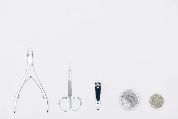 Vue de dessus des pinces à ongles, ciseaux et différentes paillettes isolés sur blanc — Photo de stock