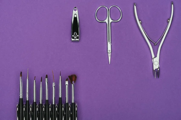 Vista superior de escovas e ferramentas de manicure isoladas em roxo — Fotografia de Stock