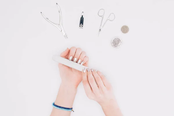 Image recadrée de femme classant des ongles avec lime à ongles isolé sur blanc — Photo de stock