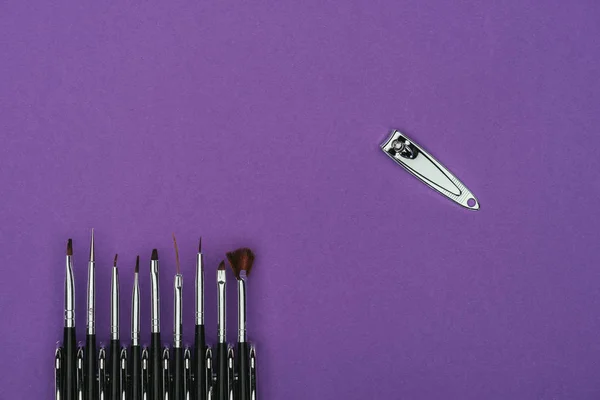 Top view of brushes and nail nippers isolated on purple — Stock Photo