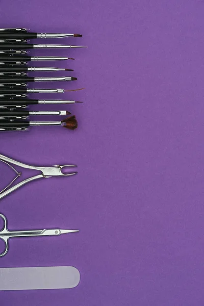 Top view of row of manicure tools isolated on purple — Stock Photo