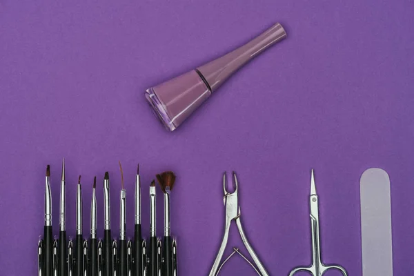 Vue de dessus du vernis à ongles et des outils de manucure isolés sur violet — Photo de stock