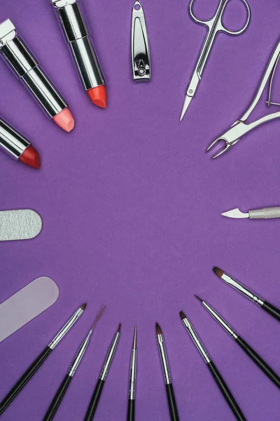 Vue de dessus du cercle de manucure et des outils de maquillage isolés sur violet — Photo de stock