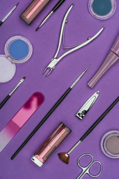 Vue de dessus de l'ensemble des outils de manucure et de maquillage isolés sur violet — Photo de stock