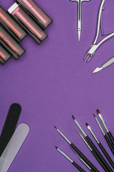 Vista superior de batons e ferramentas de manicure isoladas em roxo — Fotografia de Stock