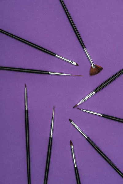 Vue de dessus des brosses dispersées isolées sur violet — Photo de stock