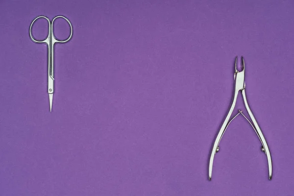 Top view of scissors and nail nippers isolated on purple — Stock Photo