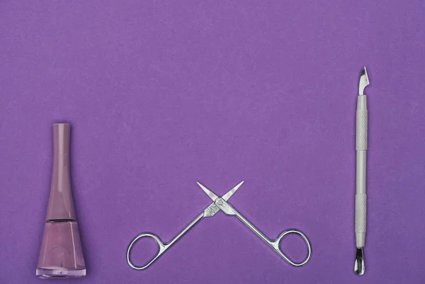 Top view of nail polish and open scissors isolated on purple — Stock Photo