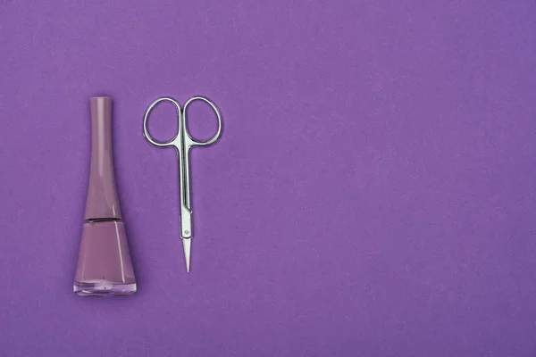 Вид зверху лак для нігтів і ножиці ізольовані на фіолетовому — стокове фото