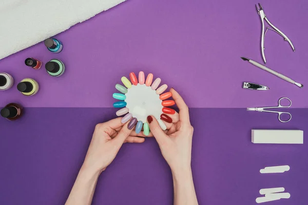 Abgeschnittenes Bild einer Frau, die Farbe für Nägel mit Maniküre-Palette wählt — Stockfoto