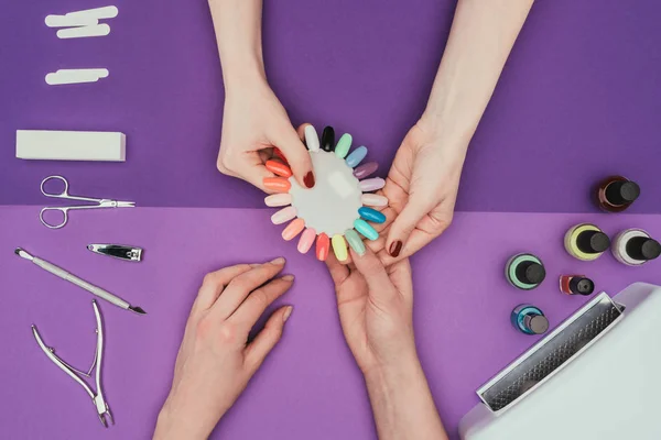 Cropped image of manicurist showing manicure palette to customer — Stock Photo