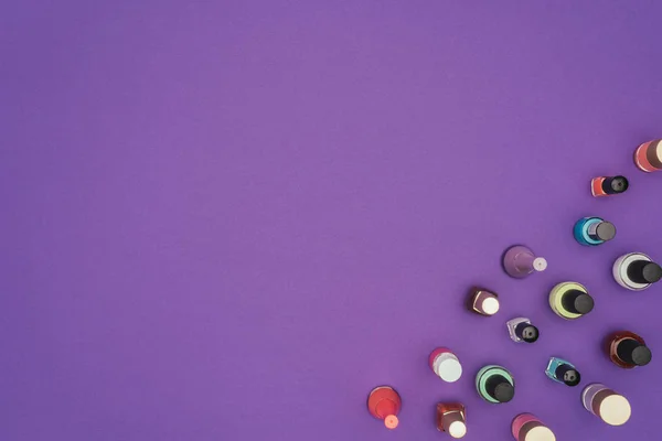 Вид сверху цветные лаки для ногтей изолированы на фиолетовый — стоковое фото