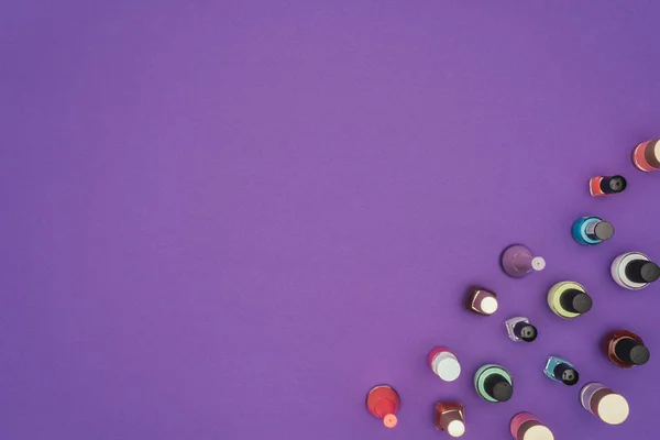 Top view of colored nail polishes isolated on purple — Stock Photo