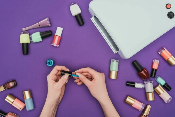 Image recadrée de fille peignant des ongles isolés sur violet — Photo de stock