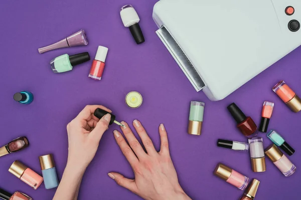 Imagem cortada de mulher pintando unhas isoladas em roxo — Fotografia de Stock