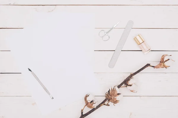 Верхний вид ножниц, пилка для ногтей и лак для ногтей с белой бумагой на деревянном столе — стоковое фото